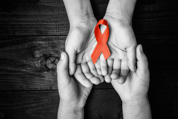 Mãos segurando um laço vermelho em referência ao Dia Mundial de Luta Contra Aids.
