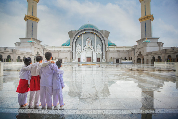 Quatro meninos muçulmanos se abraçando próximo a uma mesquita em Kuala Lumpur, na Malásia.