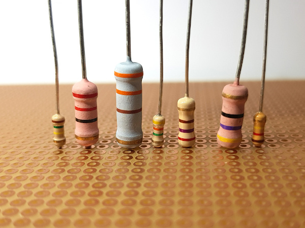 Sete diferentes modelos de resistor elétrico sobre uma mesa de madeira.
