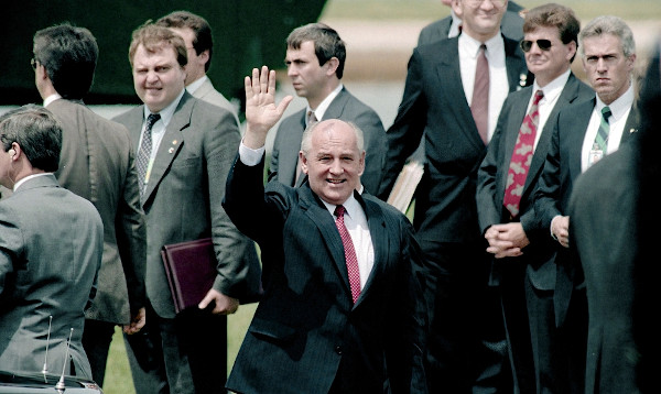 Mikhail Gorbachev acenando em meio a um grupo de homens.