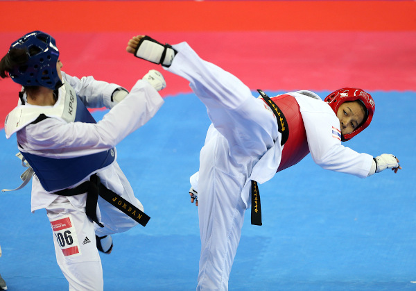  Atleta realiza tentativa de chute na cabeça da adversária durante combate de taekwondo.