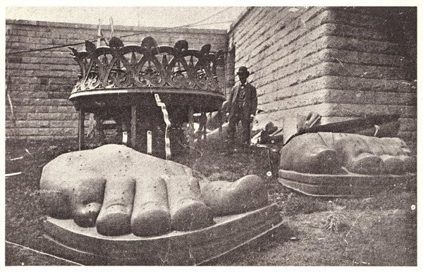 Homem próximo aos pés da Estátua da Liberdade, ainda separados do corpo da estátua durante sua construção.
