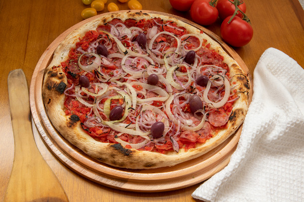 Pizza de calabresa sobre uma mesa de madeira, remetendo à história da pizza no Brasil.