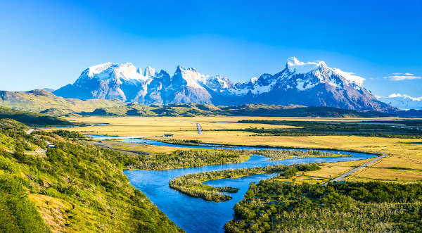 Paisagem natural, com montanhas ao fundo e rio à frente, em referência aos fatores climáticos.