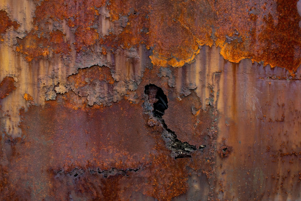 Uma superfície com várias camadas enferrujadas evidenciando os efeitos da ferrugem.