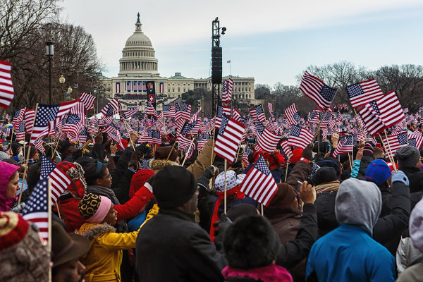 Povo segurando bandeiras em frente à Casa Branca, nos Estados Unidos, residência oficial do chefe do Estado.