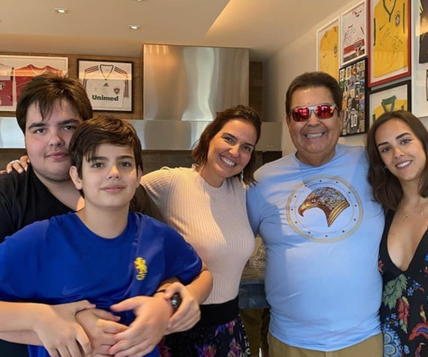 Foto de Faustão, usando óculos e camisa azul, com sua esposa Luciana e seus filhos Lara, João Guilherme e Rodrigo