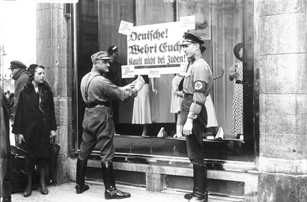 Soldados nazistas em ação discriminatória contra judeus, em referência aos riscos do nacionalismo.