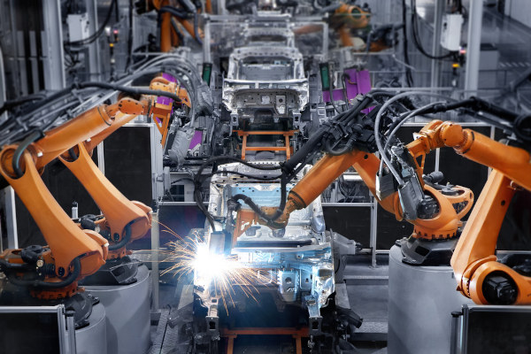 Robôs trabalhando em uma montadora de automóveis na terceira fase da Revolução Industrial.