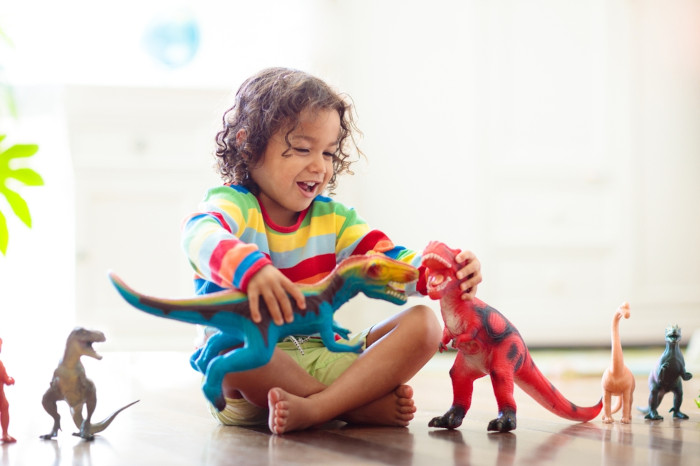 Menino brincando com brinquedos de dinossauros. 
