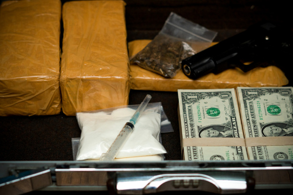 Entorpecentes e dólares em alusão ao narcotráfico.