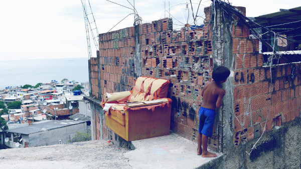 Criança no alto de uma favela, em texto sobre marginalização.
