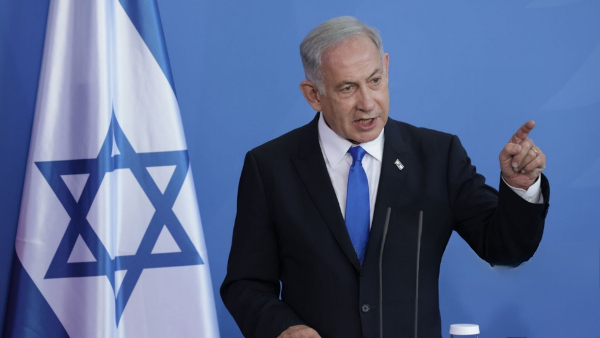 Fotografia de Benjamin Netanyahu tirada perto da bandeira do Estado de Israel.