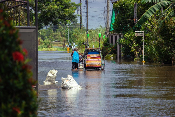 Pessoa transitando em uma enchente, situação que pode estar ligada à leptospirose.