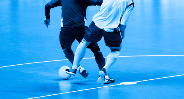 Jogador driblando o jogador do time adversário em uma partida de futsal.