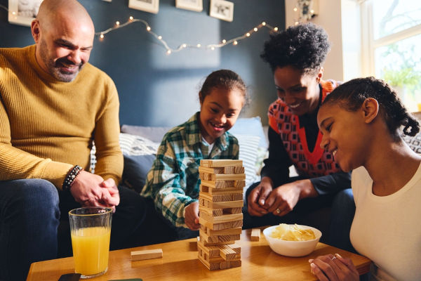 Família reunida brincando com jogo de madeira, uma das opções de atividades para o Dia das Crianças.