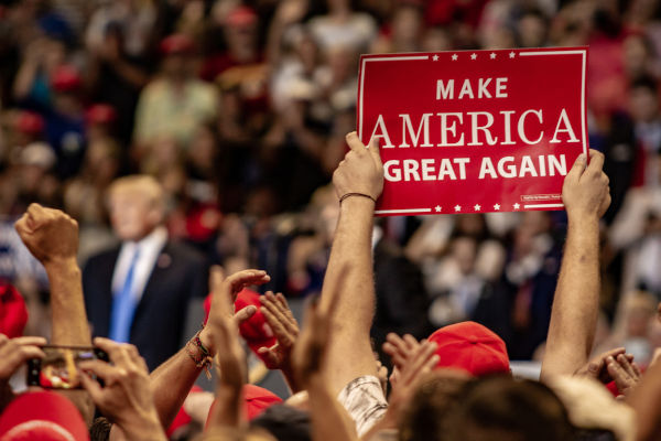 Apoiador de Donald Trump segura placa com o slogan da campanha do governo Trump: Make America Great Again.[1]