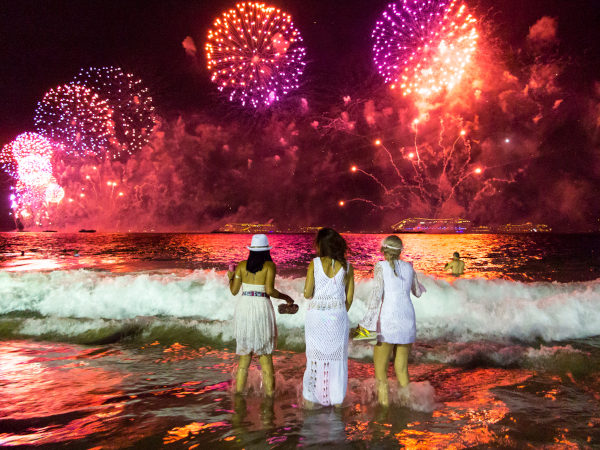 Mulheres pulando ondas durante o show de fogos de artifício do Ano-Novo ou do Réveillon.