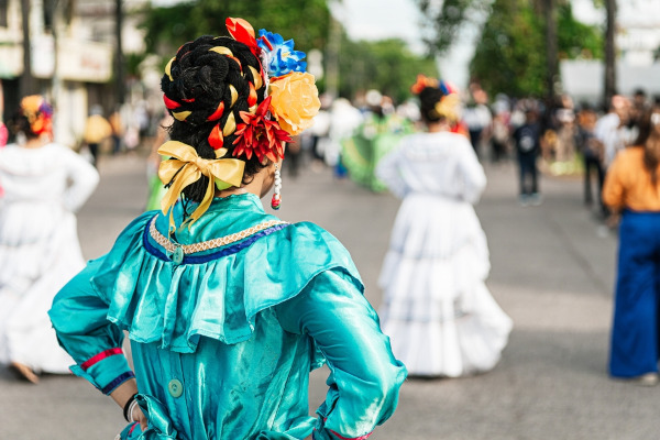 Mulheres de costas, vestidas com vestidos amplos e flores no cabelo, trajes culturais de Honduras.