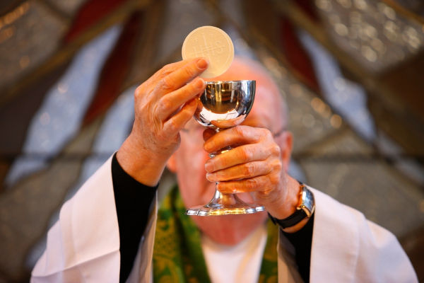 Padre levantando os elementos ligados à Eucaristia, celebrada no Corpus Christi.