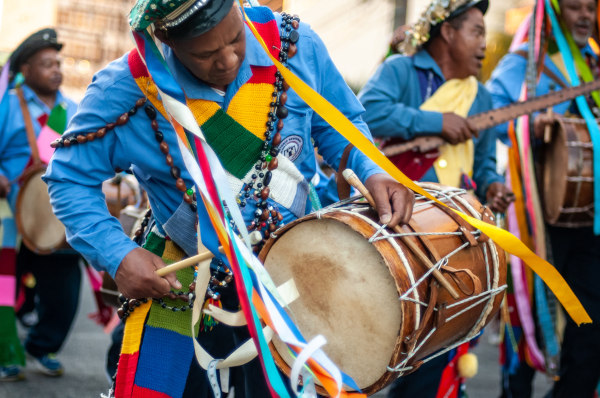 Mulher de cor parda, resultado da miscigenação étnica no Brasil. Homens tocando tambores na Festa do Congo, exemplo de miscigenação cultural.