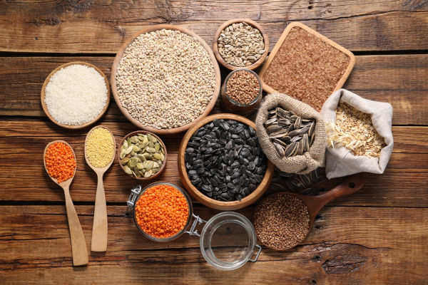 Vários tipos de grãos e cereais sobre uma mesa, exemplos de alimentos de origem vegetal.