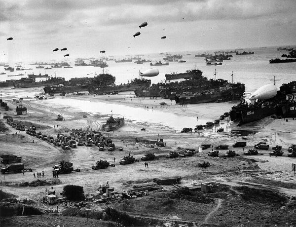 Veículos, navios e dirigíveis sobre a praia de Omaha, durante a operação de desembarques na Normandia.