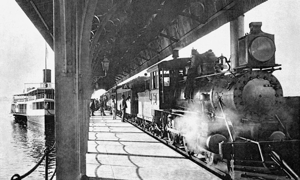 Na fotografia, barca e trem chegando ao píer Barão de Mauá.