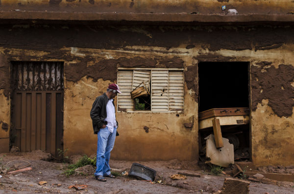 Pessoa olhando sua casa destruída, uma das consequências do rompimento da barragem de Mariana.