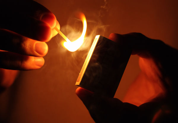 Pessoa acendendo um palito de fósforo e emitindo fogo.