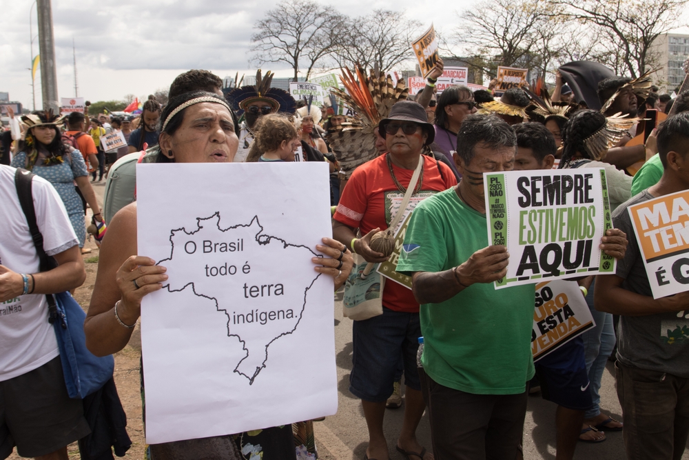 Indígenas segurando cartazes em protesto contra o marco temporal.