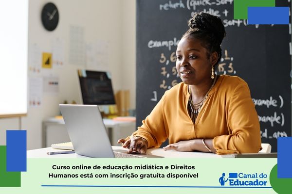 Curso online e gratuito de educação midiática e Direitos Humanos Professore de pele preta e blusa amarela em sala de aula a frente de um computador portátil