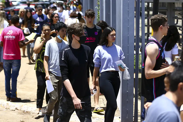 Estudante realiza redação. Texto na imagem: 12 possíveis temas para a redação do Enem.