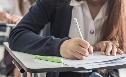 Estudante negra apontando com o dedo e sorrindo, fundo amarelo