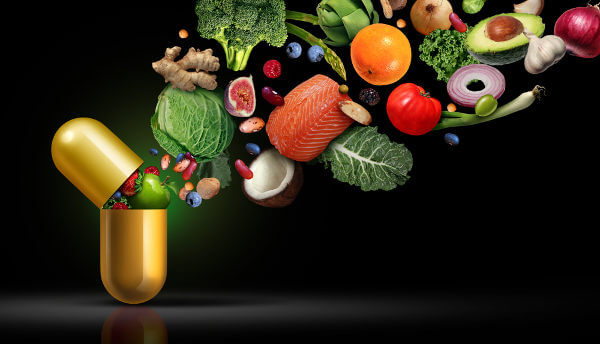 Vegetais saindo de uma cápsula de remédio para representar a suplementação de vitaminas.