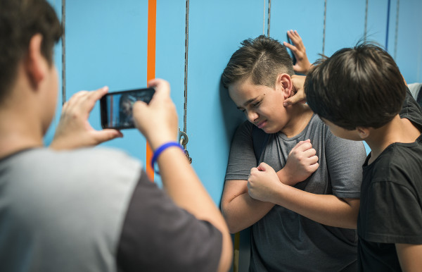 Menino filmando colegas brigando, demonstrando a ideia de bullying