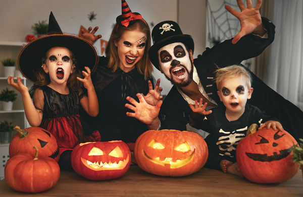 Família fantasiada junto com abóboras decoradas para o Halloween.