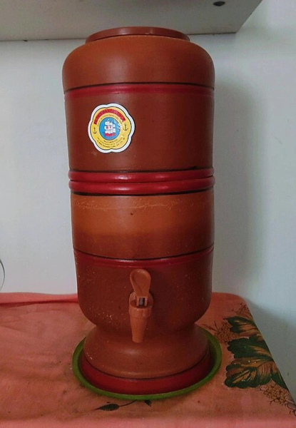Mãos utilizando escorredor de arroz, uma invenção brasileira. Filtro de barro, uma invenção brasileira.