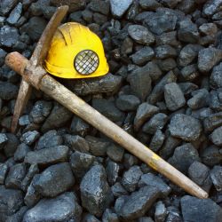 pedras, capacete amarelo e instrumento de mineração