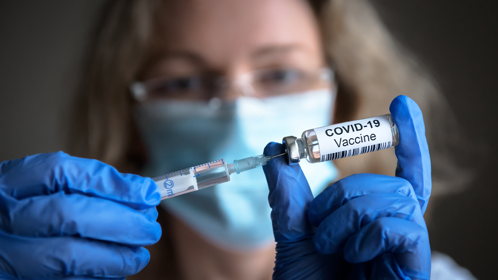 Mulher com máscara segura vacina contra Covid